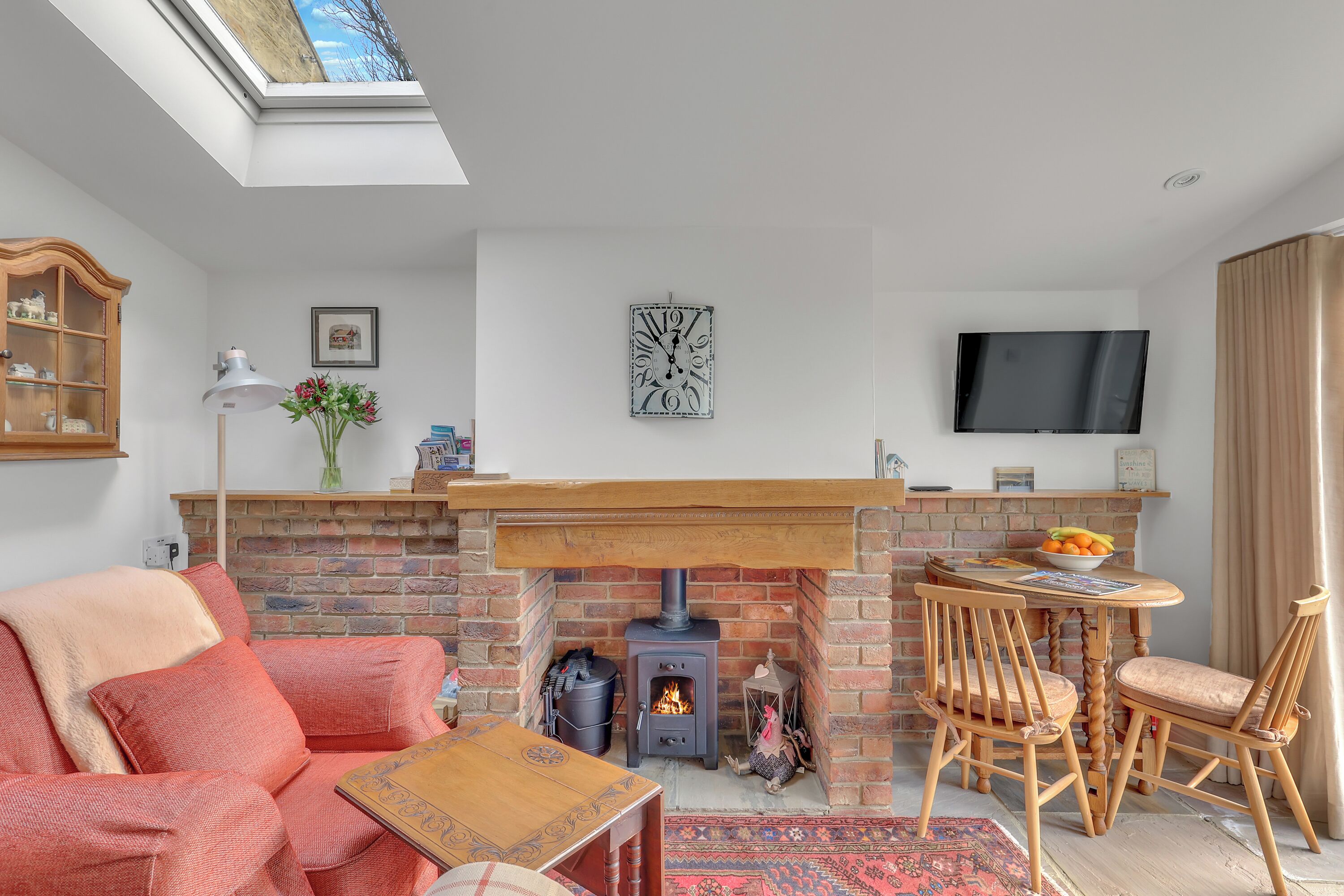 A cozy living room with a brick fireplace, a wooden table, and a comfortable sofa.