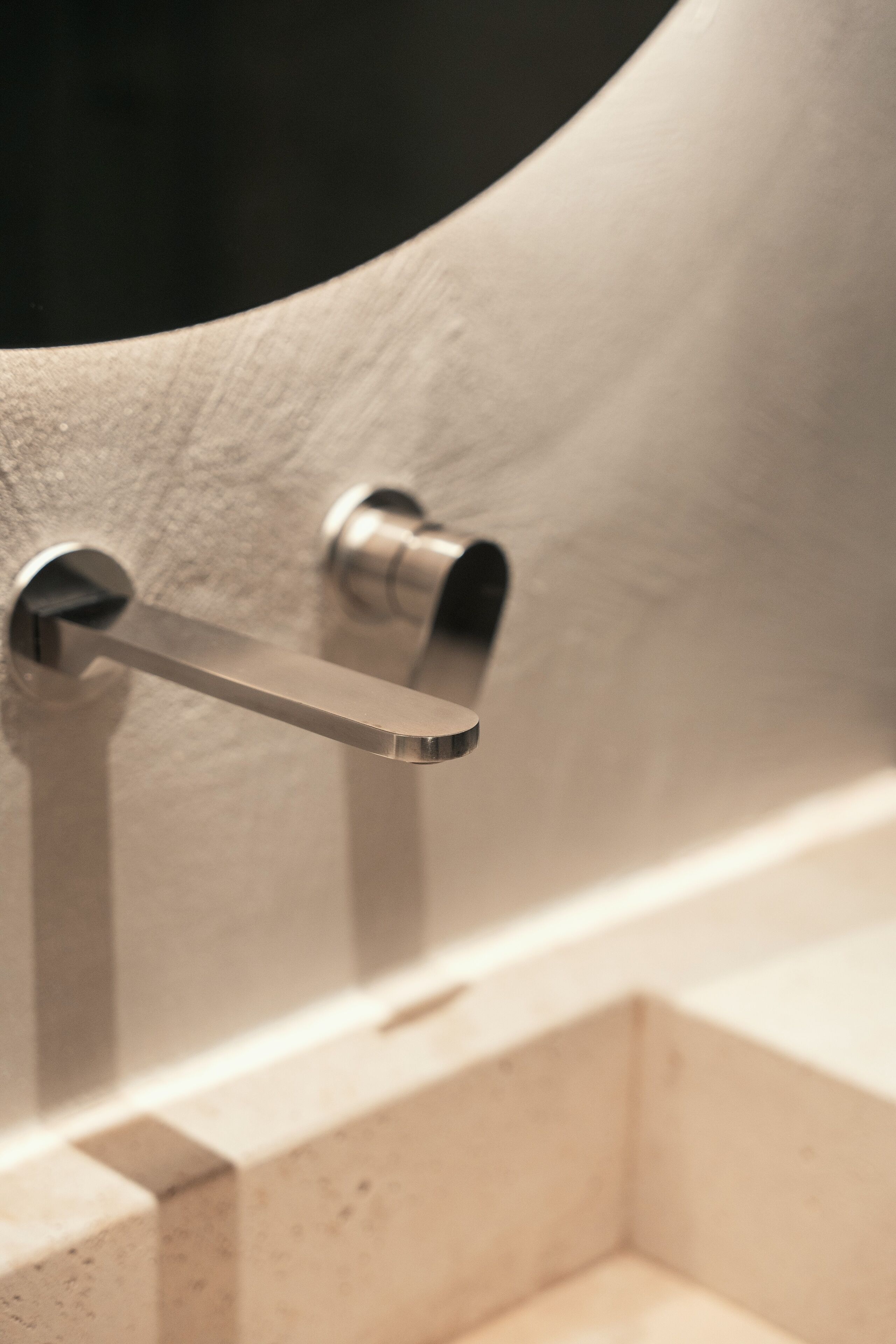 A metallic towel bar attached to a textured wall, likely part of a bathroom or similar setting.