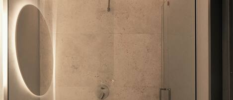 Un baño moderno con cabina de ducha de vidrio, un espejo grande y encimera de mármol.