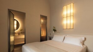 A hotel room with a large bed, a bedside table, a nightstand, a wall-mounted light fixture, and a mirror with a light. - VELVET GREY BOUTIQUE HOTEL ROMA (Rome)