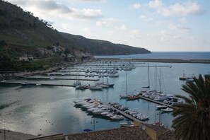 Un port de plaisance où sont amarrés de nombreux bateaux, entouré de collines et surplombé par un ciel dégagé.