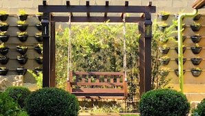 A garden with a wooden swing, potted plants on a wall, and a flower bed with marigolds.
