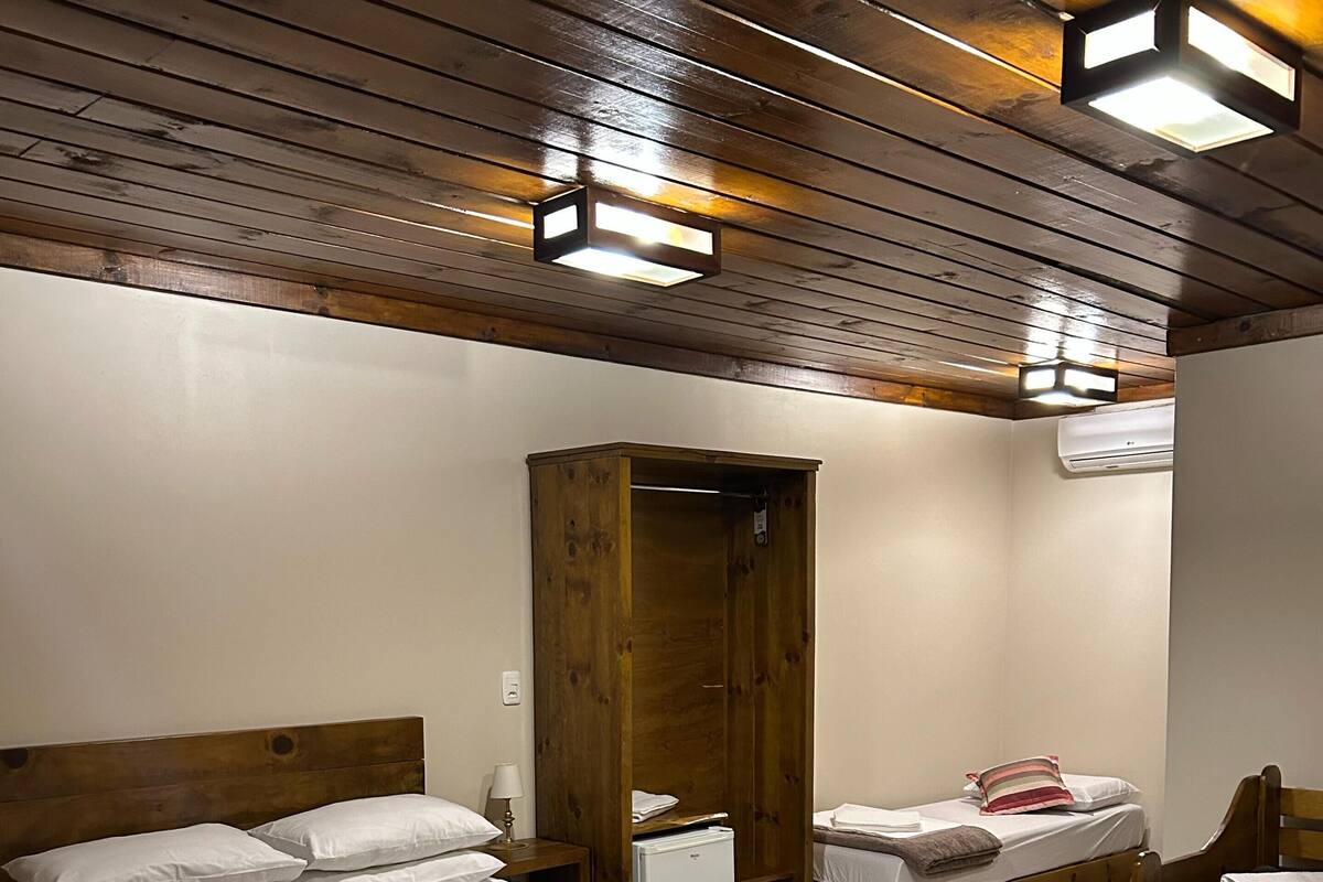 A room with a large bed, two smaller beds, a wardrobe, and a ceiling light fixture.