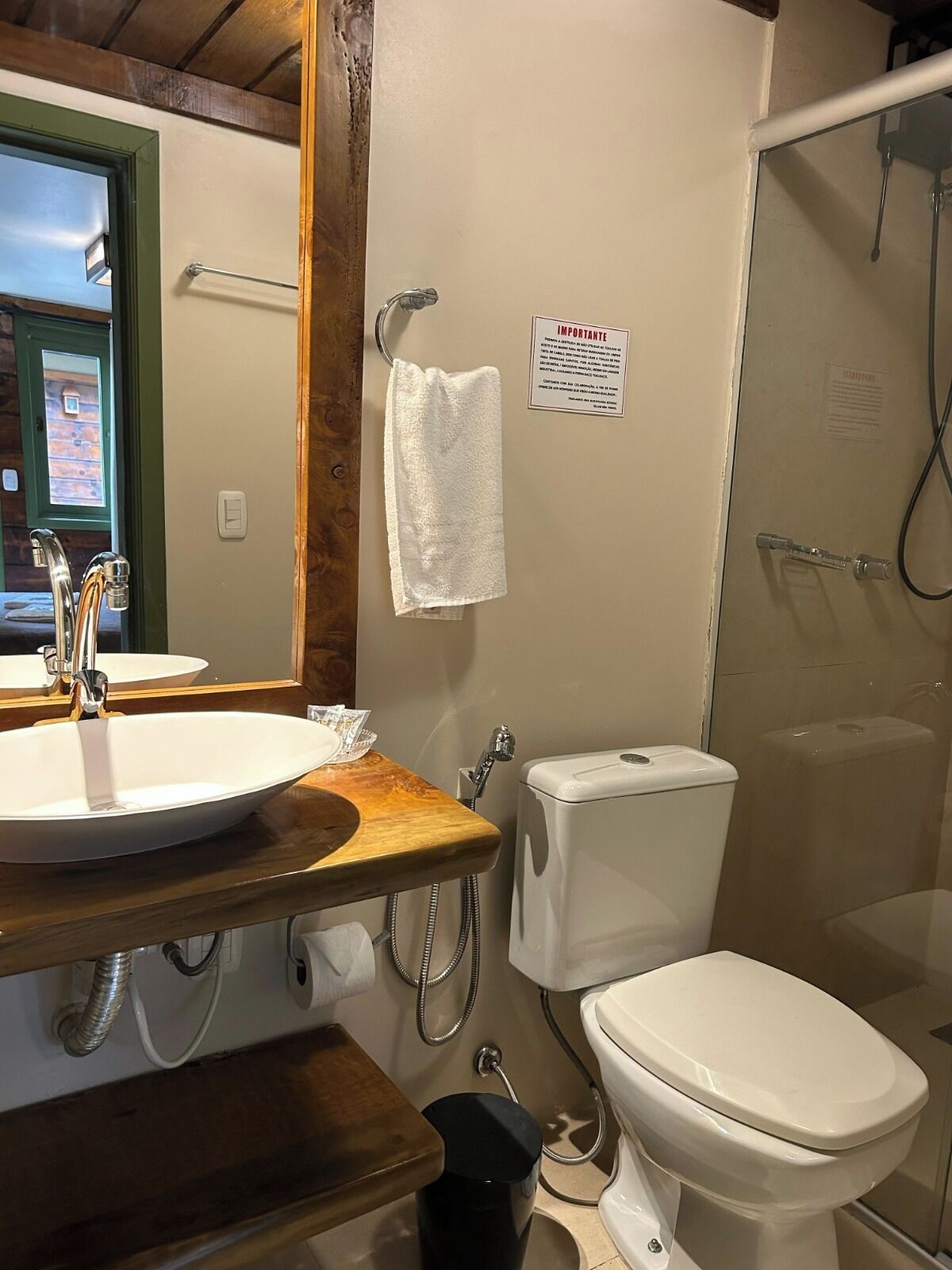 Een badkamer met een houten wastafel, een wasbak, een toilet en een douche.