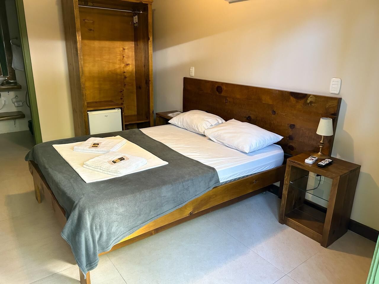 A single bed with a wooden headboard, a bedside table with a lamp, and a small shelf.