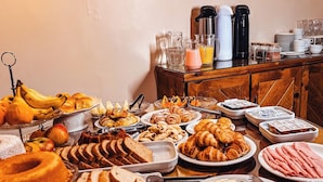 A buffet with various food items including bread, pastries, and fruits.