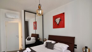 Habitación de hotel con una cama grande, una mesita de noche, un espejo y una obra de arte roja en la pared.