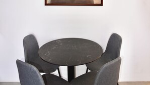 Un cuadro abstracto enmarcado en una pared, sobre una mesa redonda con cuatro sillas grises.