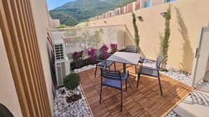 Un patio con mesa y sillas, rodeado por una valla blanca y macetas con plantas.