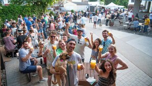 Un grupo de personas reunidas al aire libre, sentadas en mesas, algunas sosteniendo bebidas.
