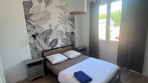 A bedroom with a bed, nightstands, a wall-mounted lamp, and a window with curtains. - House in Narbonne, ideal for Les Grands Buffets, with swimming pool and air-conditioning (Narbonne)