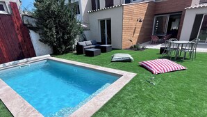 A swimming pool with artificial grass, a wooden deck, and outdoor furniture. - House in Narbonne, ideal for Les Grands Buffets, with swimming pool and air-conditioning (Narbonne)