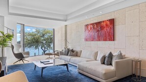 Una sala de estar moderna con un ventanal grande, un sofá color beige, una mesita de centro y un tapete azul.
