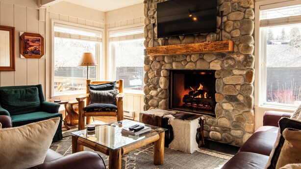 A cozy living room with a stone fireplace, comfortable seating, and a flat-screen TV mounted above the hearth.