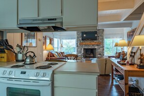 Una cocina con estufa, un comedor con mesa y sillas, y una sala de estar con chimenea.