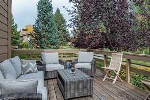 A covered outdoor seating area with wicker furniture and a wooden deck.