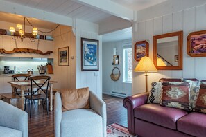 Ein gemütliches Wohnzimmer mit einer Ledersofa, einem Essbereich mit Holztisch und einer im Hintergrund sichtbaren Küche.