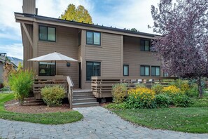 A modern two-story building with a covered outdoor seating area and a landscaped garden.