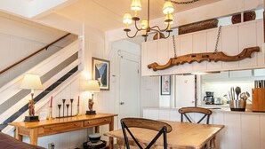 A dining area with a wooden table and chairs, a chandelier, and a staircase with a railing.