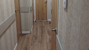 Un pasillo estrecho con suelo de madera y paredes de colores claros.
