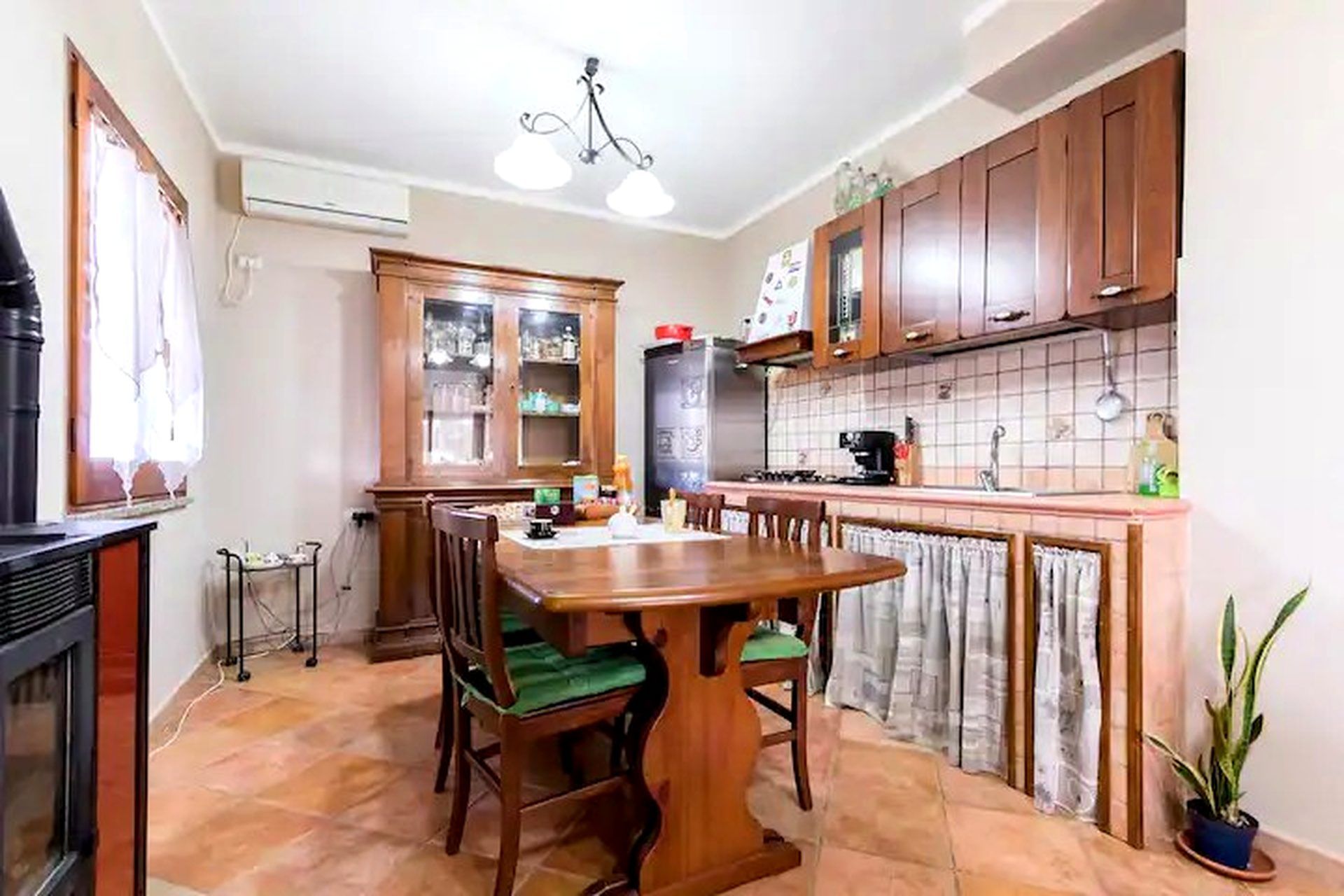 A kitchen with wooden cabinets, a dining table with chairs, a stove, and a refrigerator.