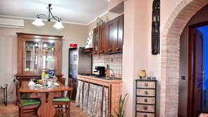 Una cocina con mesa de madera, armarios y pared de ladrillo.