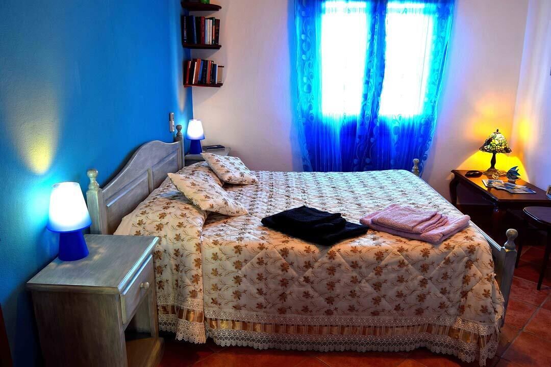 Une chambre à coucher avec un lit, des lampes de chevet, une table de chevet, une bibliothèque et une fenêtre avec des rideaux.