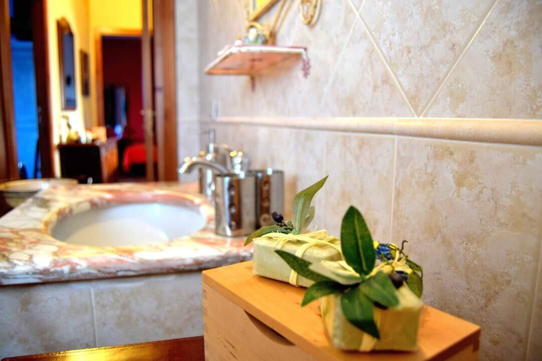 Un baño con lavamanos de mármol, tocador de madera y espejo.