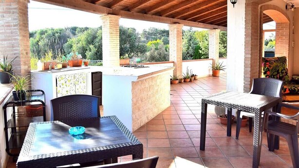 Un patio al aire libre con techo de madera, una barra y diferentes disposiciones de asientos.