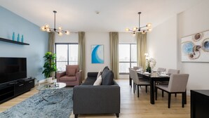 Een moderne woonkamer met een flatscreen televisie, bank en een eethoek met stoelen en een tafel.