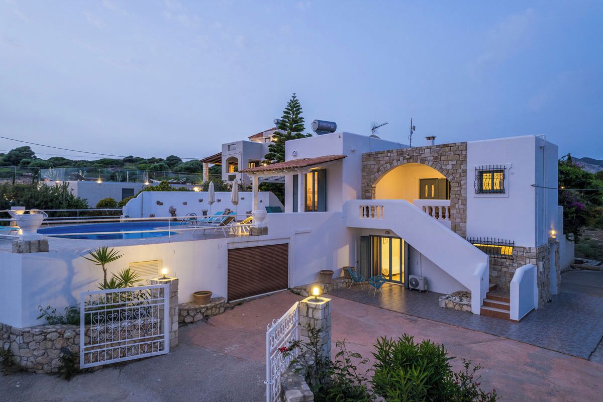 A modern villa with a swimming pool, outdoor seating, and a stone staircase.
