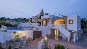 En moderne villa med swimmingpool, udendørs siddepladser og en stentrappe.