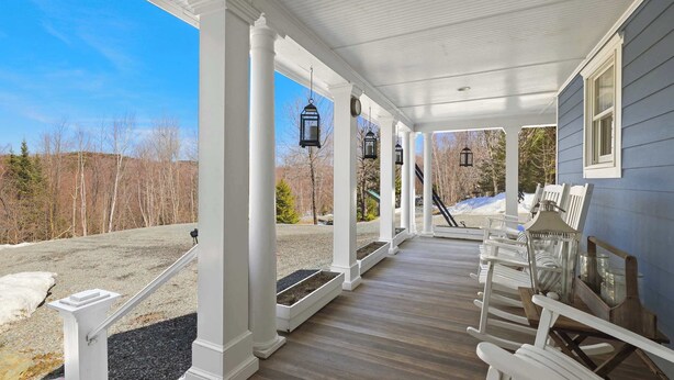 A covered porch with white columns, black lanterns, and outdoor seating. - Forest Retreat | 25 Min to Stratton (Windham)