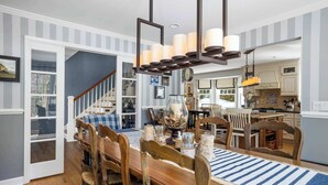 A dining area with a wooden table, chairs, and a striped rug. There is a staircase leading to another room. - Forest Retreat | 25 Min to Stratton (Windham)