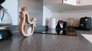 Un comptoir de cuisine avec une machine à café, une bouilloire et un objet décoratif en bois.