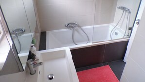 Une salle de bain avec une baignoire, une douche et un lavabo.