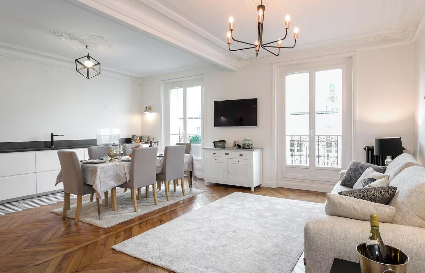 Un soggiorno moderno con zona pranzo, un divano bianco, TV e un balcone con vista.