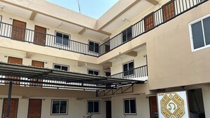 Un edificio residenziale a più piani con balconi numerati e un'area di parcheggio coperta.