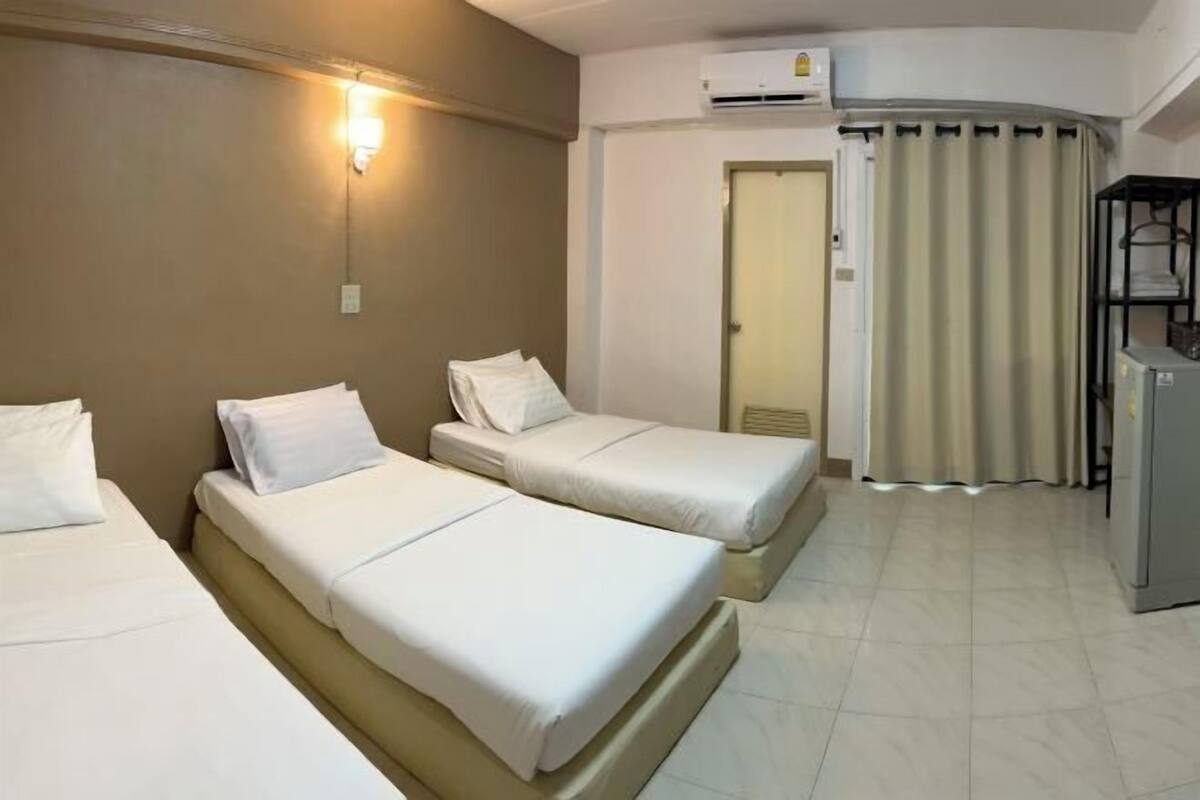 Habitación de hotel con dos camas, un armario, un escritorio y un aire acondicionado.