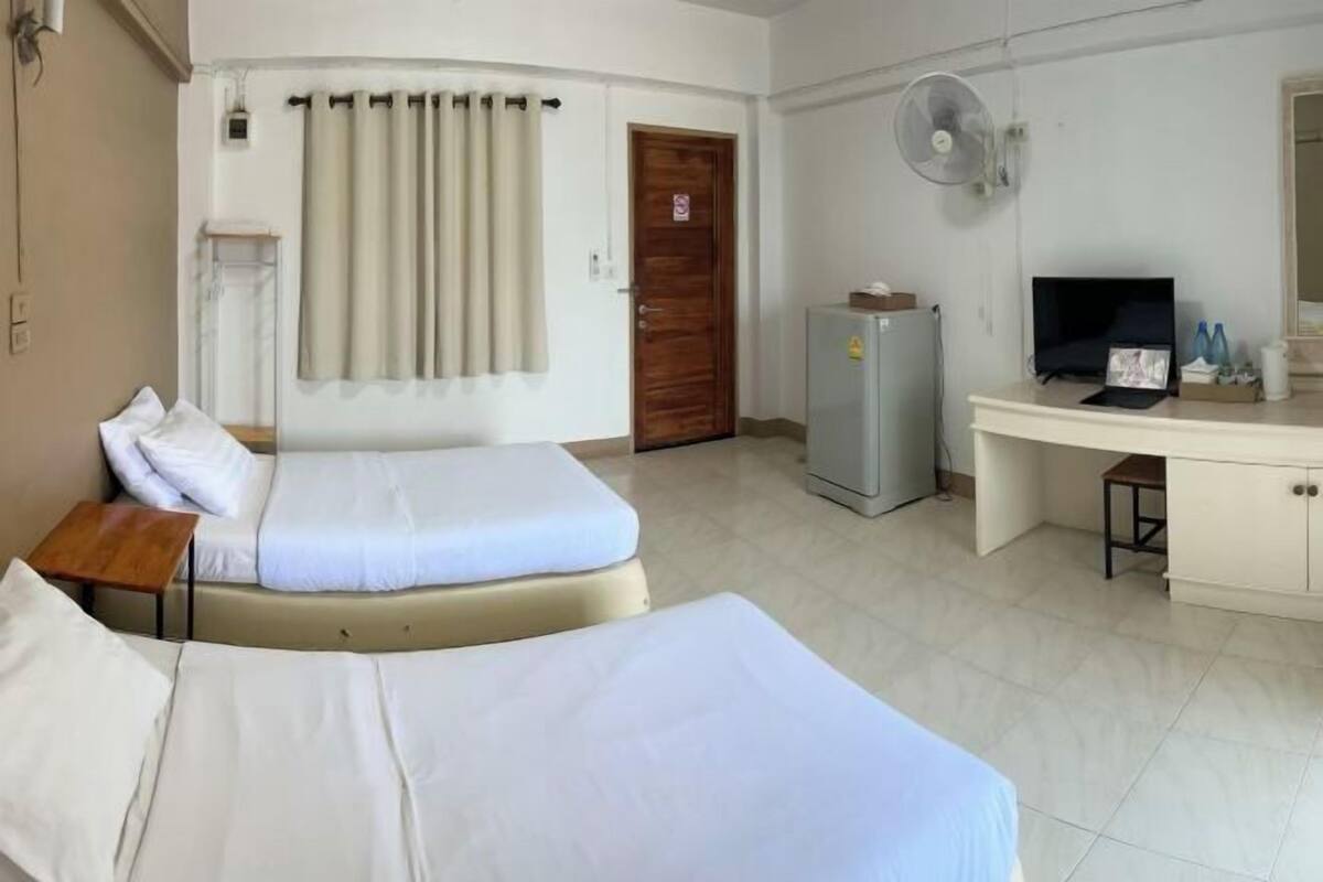 Habitación de hotel con dos camas, un escritorio, televisor, refrigerador y cortina.