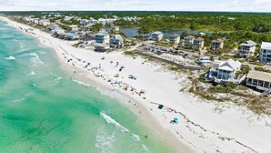An aerial view of a coastal area with a beach, beachfront properties, and a clear sky. - LakeFront w/ LSV, Bikes, Pool, & Game Room! STEPS to Beach! Sleeps 20, Pet Friendly! (Santa Rosa Beach)
