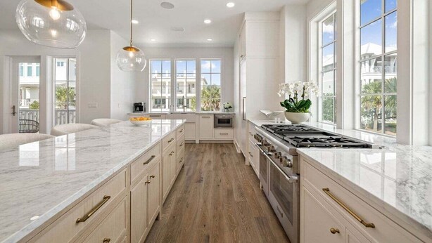 A spacious kitchen with a large island, white cabinetry, and a view of the outdoors through large windows. - LakeFront w/ LSV, Bikes, Pool, & Game Room! STEPS to Beach! Sleeps 20, Pet Friendly! (Santa Rosa Beach)