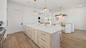 A spacious kitchen with a large island, wooden flooring, and pendant lighting. - LakeFront w/ LSV, Bikes, Pool, & Game Room! STEPS to Beach! Sleeps 20, Pet Friendly! (Santa Rosa Beach)