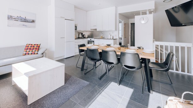 A modern, well-lit apartment with a dining area, kitchen, and living space.