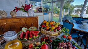 Ein Frühstückstisch mit Früchten, einem Obstkorb und einer dekorativen Vase mit Blumen.