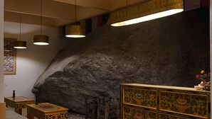 Ein Zimmer mit Holzeinrichtung, einer großen Felswand und hängenden Pendelleuchten.