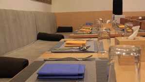 Ein Essbereich mit einem langen Tisch, gedeckt für eine Mahlzeit, einschließlich Besteck, Servietten und Gläsern.