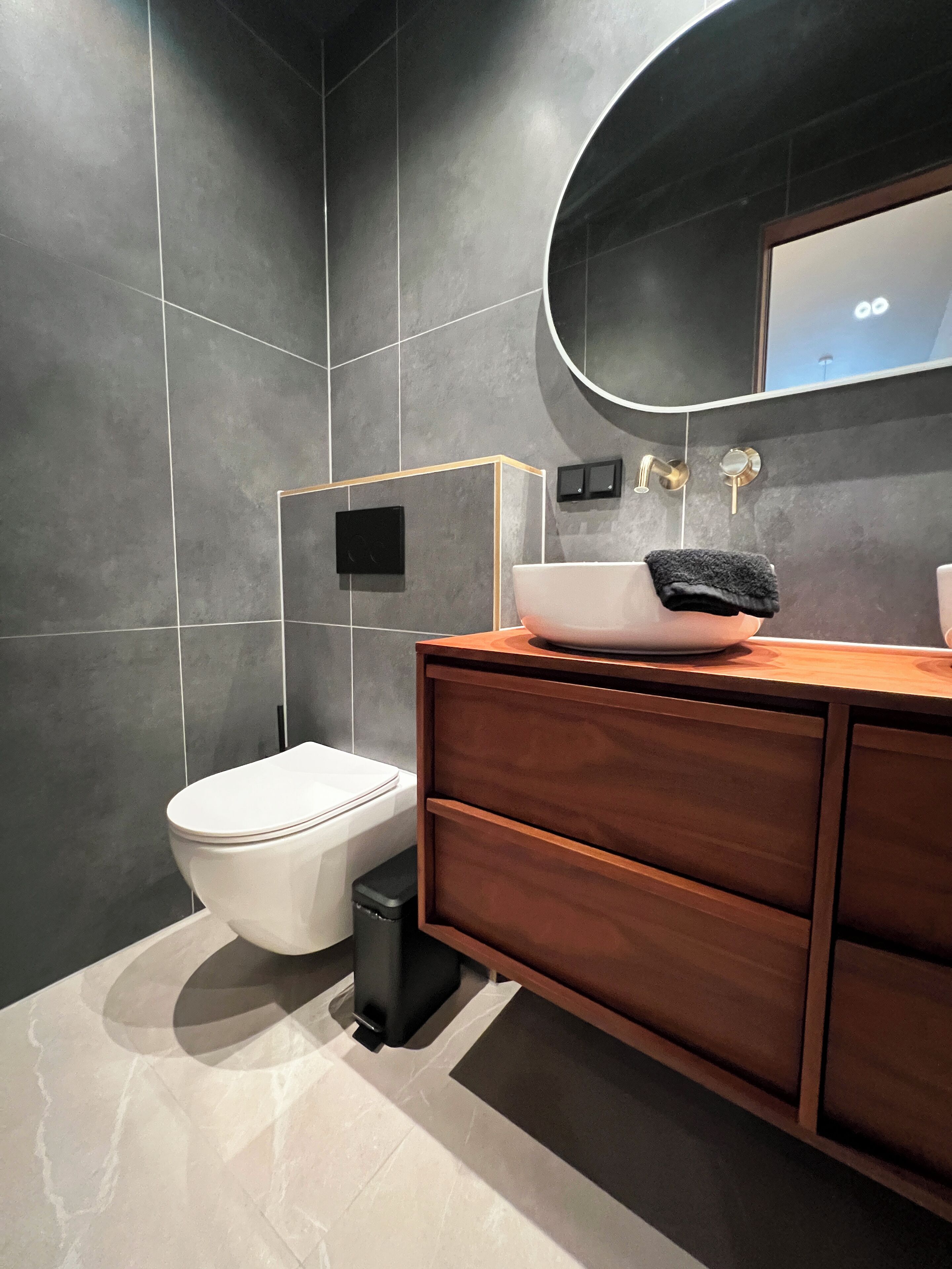 A modern bathroom with a toilet, vanity, and a mirror.