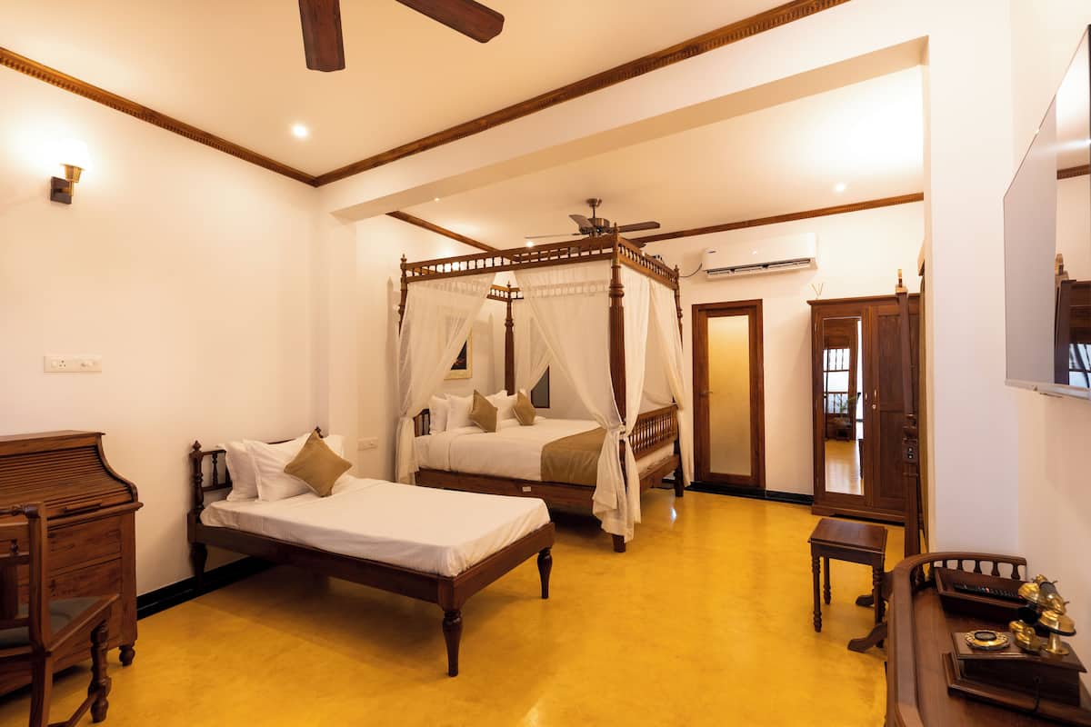 A bedroom with a four-poster bed, a desk, and a chair.