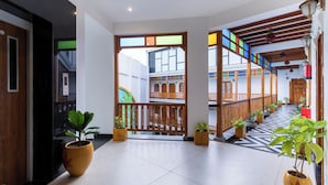 A modern hotel lobby with a central wooden staircase, potted plants, and a patterned floor. - La Moon Puducherry (Puducherry)